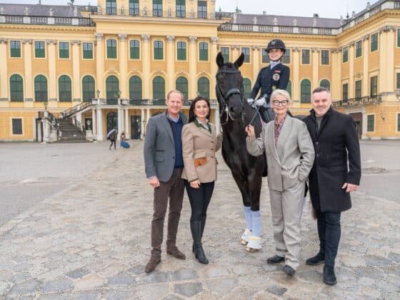 Reiterin auf Pferd mit Begleitern vor Schloss in Wien.
